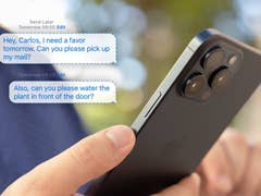 A person holding the iPhone 15 Pro Max and some messages popping up from it.