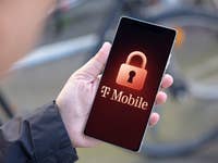 A hand holding a smartphone displaying the T-Mobile logo with a padlock icon.