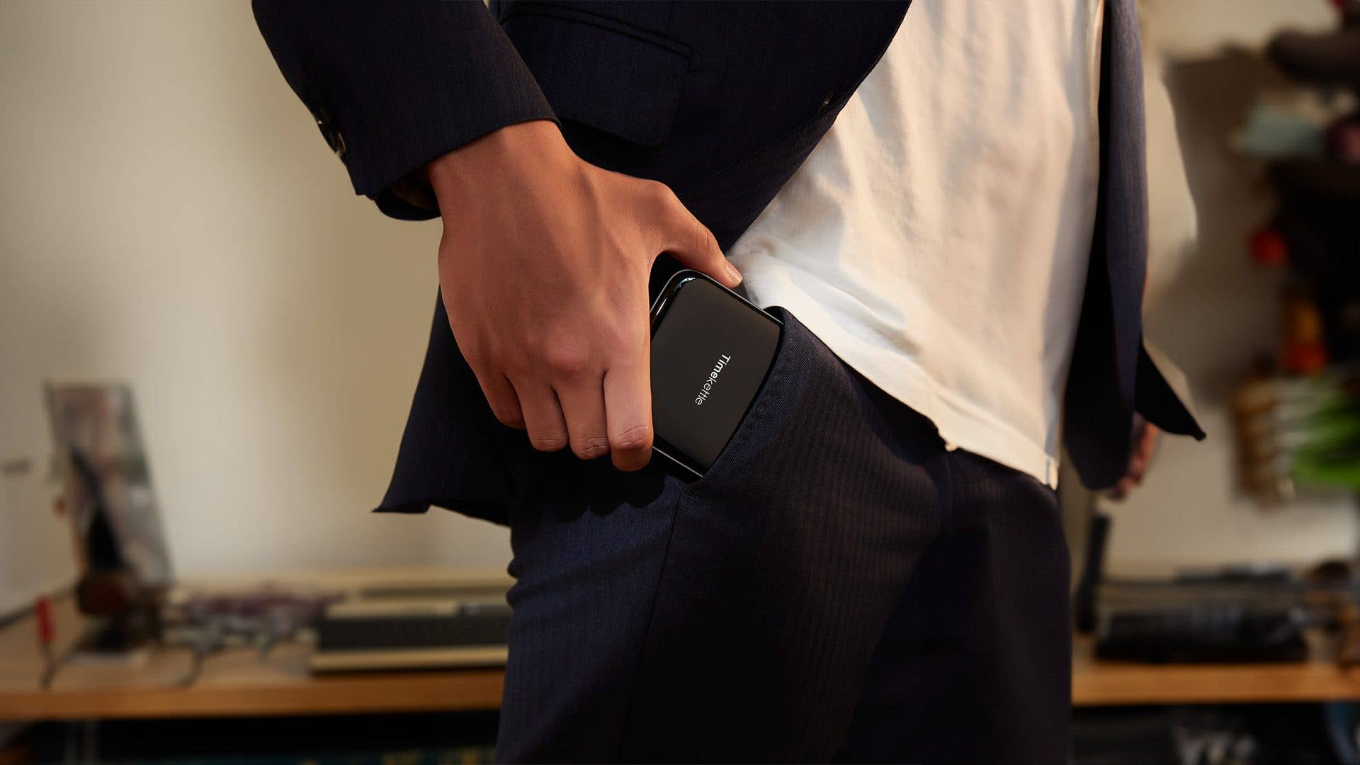 A person in a suit holds a Timekettle W4 Pro device in their pocket.
