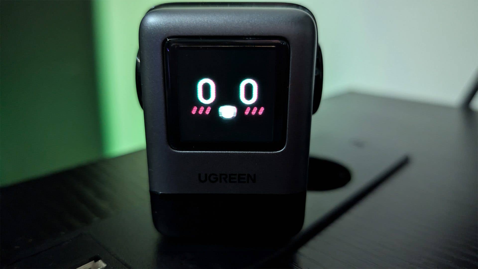 A Ugreen Uno 100W charger with a digital display showing '00' and a smiling face.