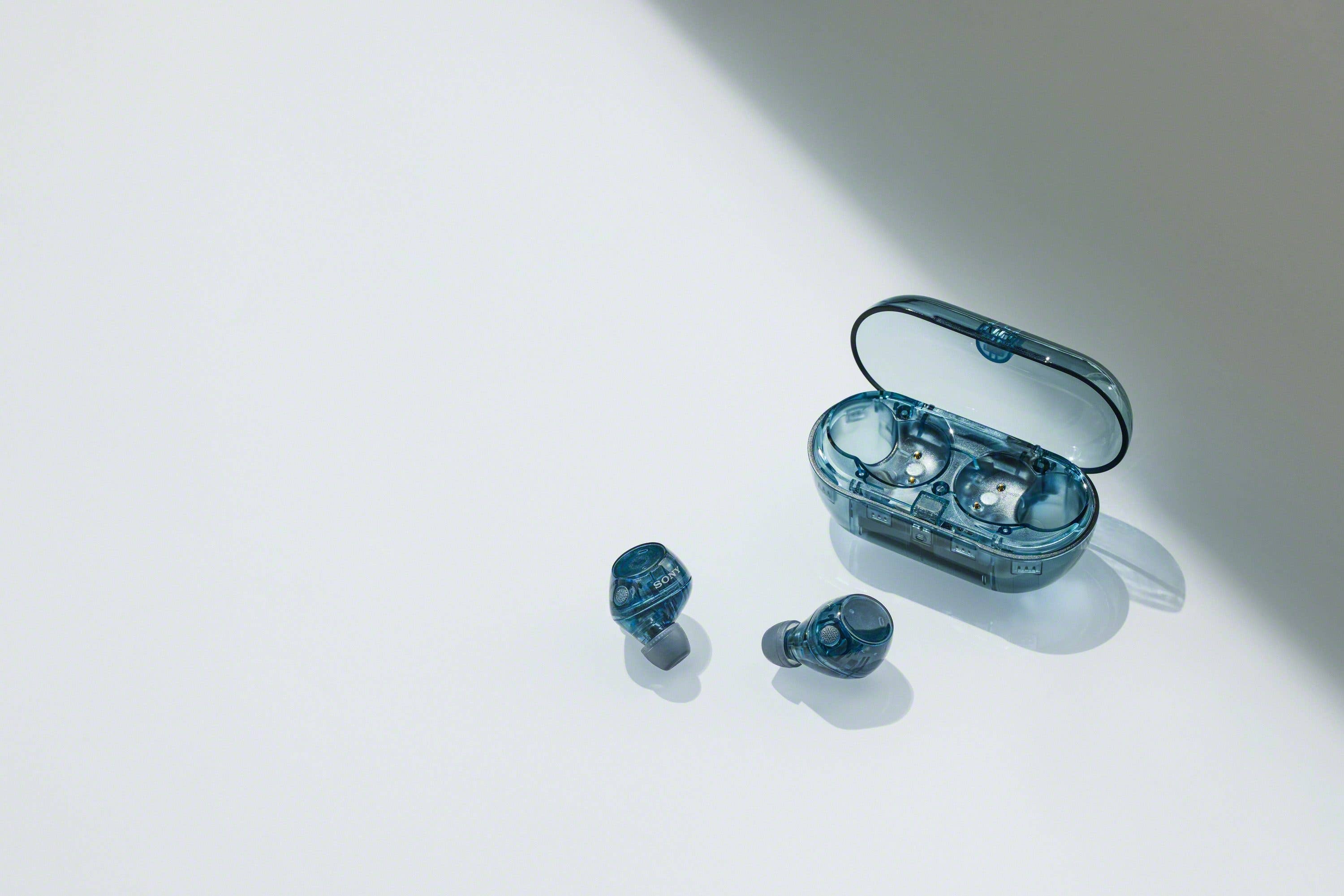 Blue Sony wireless earbuds with a charging case on a light surface.