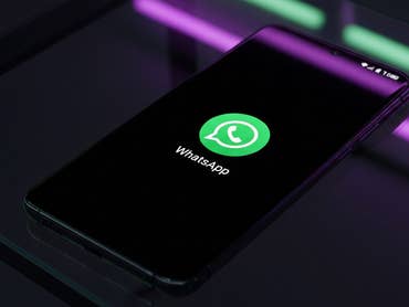 Ein Smartphone zeigt das WhatsApp-Logo auf einem schwarzen Bildschirm.