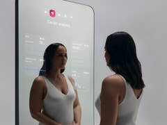 A woman interacts with the Withings OMNIA smart mirror displaying cardio analysis data.