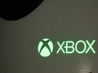 Close-up of an illuminated green Xbox logo on a console.