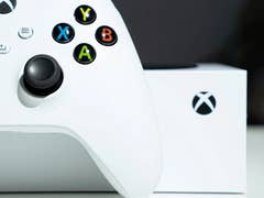An Xbox controller in white with colorful buttons next to an Xbox box.