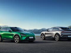 Two cars, one green and one gray, parked against a scenic mountain backdrop with the text 'Xiaomi YU7' visible.