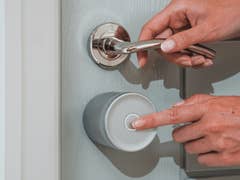 A person using a Yale Linus Smart Lock L2 Lite on a door, pressing a button.