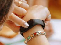 A person checking a black fitness tracker on their wrist.