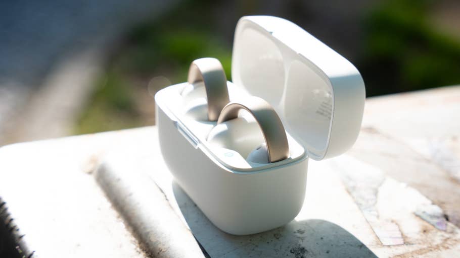 Close-up of the Soundcore Aeroclip earbuds in their charging case, placed on a textured surface.
