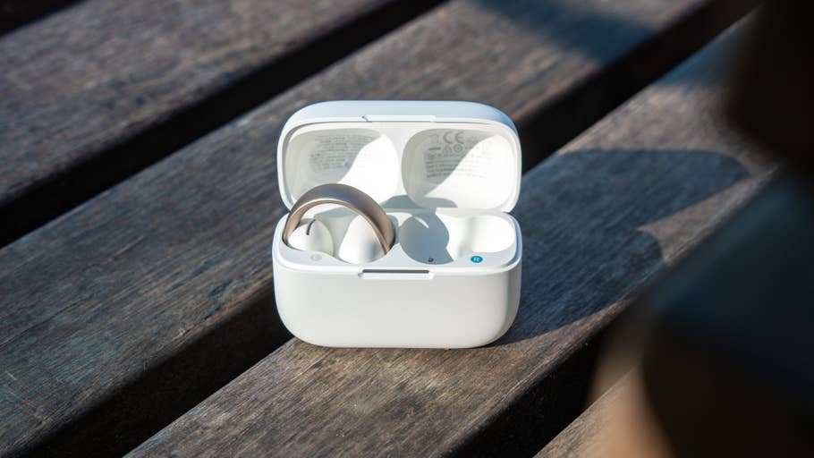 An open case with Ankeru0027s Soundcore Aeroclip earbuds resting on a wooden surface.