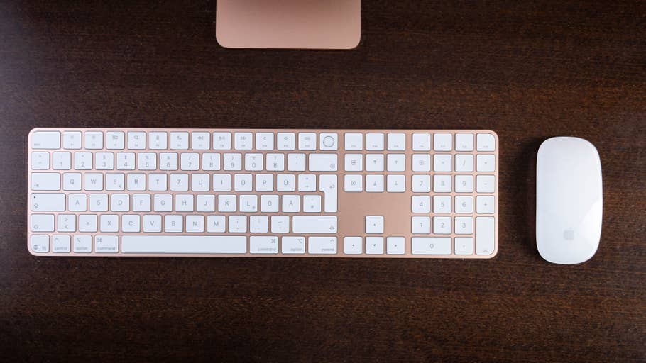 Apple keyboard and mouse on a wooden surface, with sleek design and white keys.