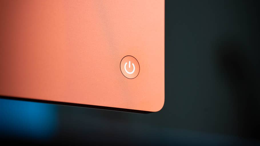 Close-up of the power button of an orange iMac.