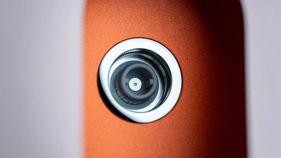 Close-up of the lens of an Apple iMac M4 2024, showing its sleek design and orange finish.