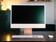 A sleek Apple iMac M4 2024 on a wooden desk, featuring a blank screen, keyboard, and mouse.