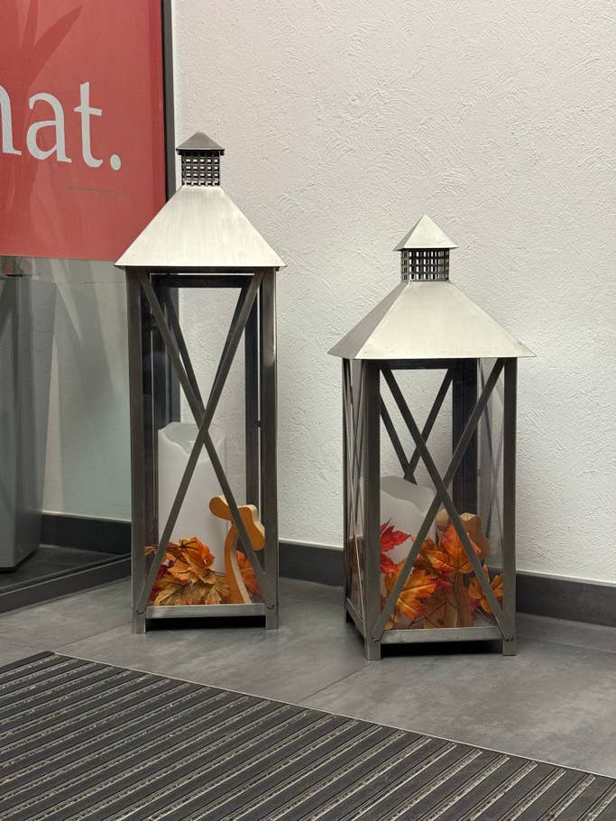 Two decorative lanterns with autumn leaves inside, next to a red u0027Whatu0027 sign.