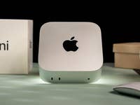 Apple Mac Mini M4 2024 on a surface with a mouse and boxes in the background.