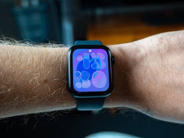 A close-up of an Apple Watch SE 3 on a wrist displaying a colorful abstract watch face.