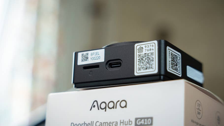 Aqara Doorbell Camera Hub G410 with labels and ports visible on a blurred background.
