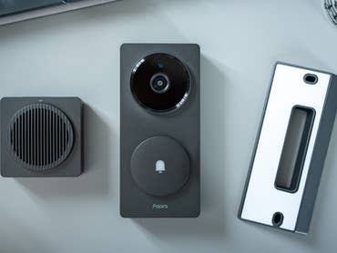 Aqara G410 doorbell camera hub with speaker and mounting plate on a light surface.
