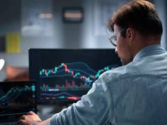 Person sitting at a computer showing stock prices