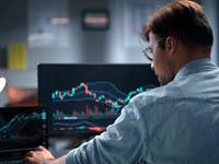 Person sitting at a computer showing stock prices