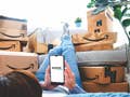 Amazon Prime logo on a mobile screen in front of piles of Amazon delivery boxes