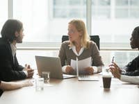 Women and men sitting at an office meeting room table