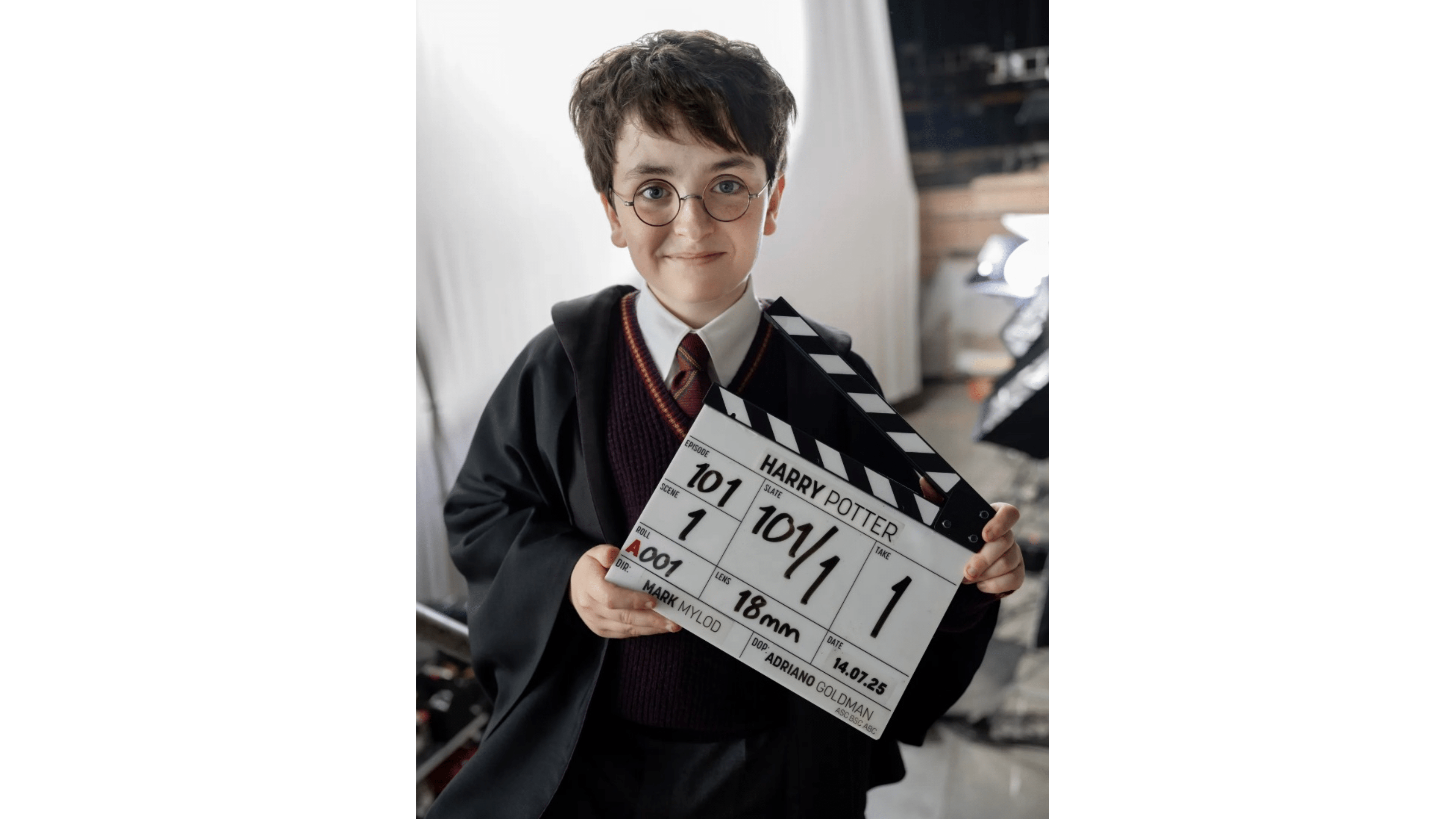 Child actor holding a clapperboard labeled 'HARRY POTTER' on a film set.