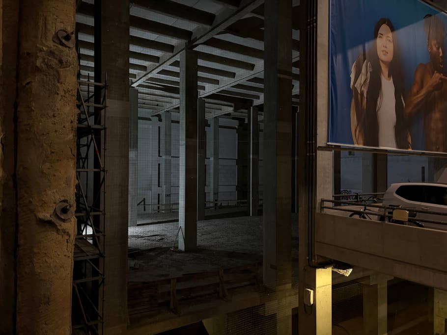 An empty construction site, illuminated by a single light source, with concrete pillars.