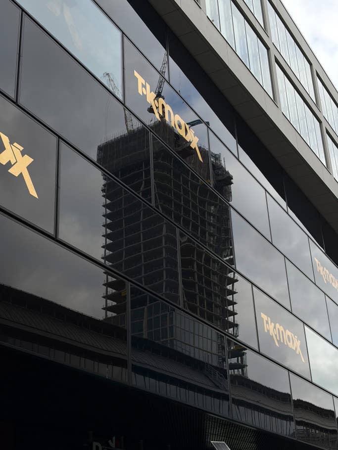 Reflection of a construction site in a glass building with TK Maxx signage.