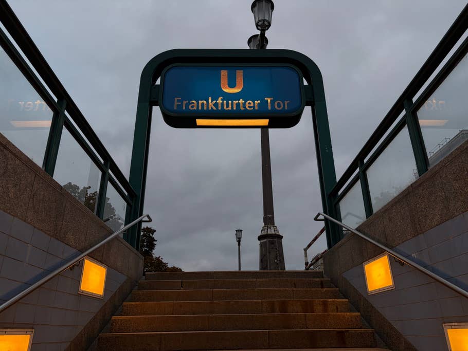 Sign of the Frankfurter Tor subway station with a cloudy sky and stairs leading up.
