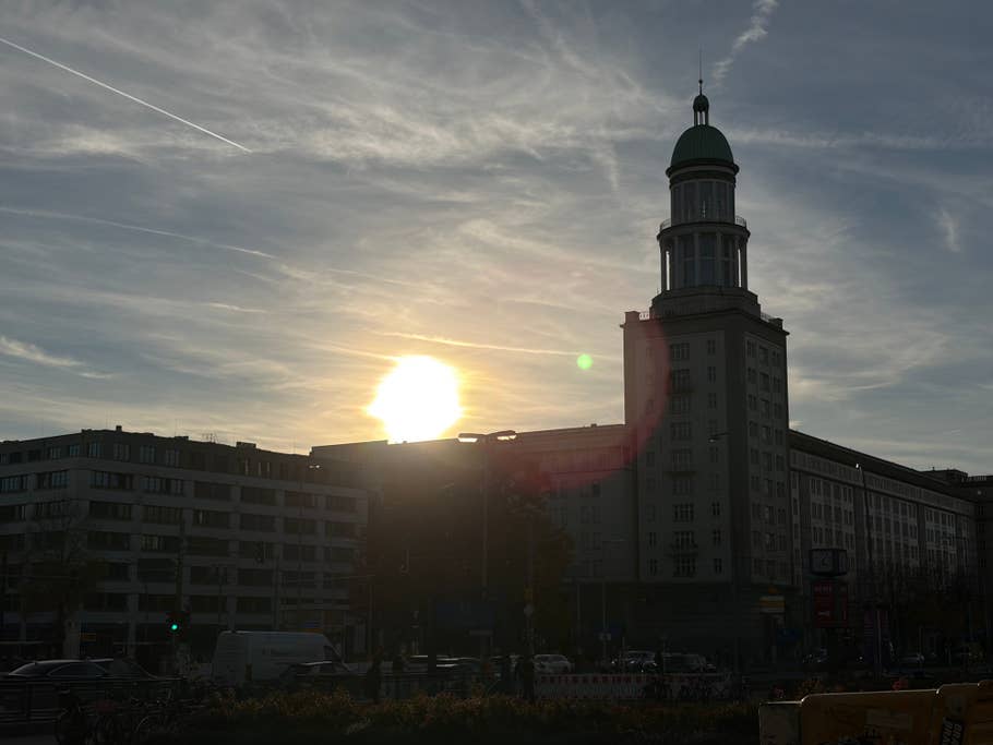 Silhouette of a building with a green dome and sunset in the background.