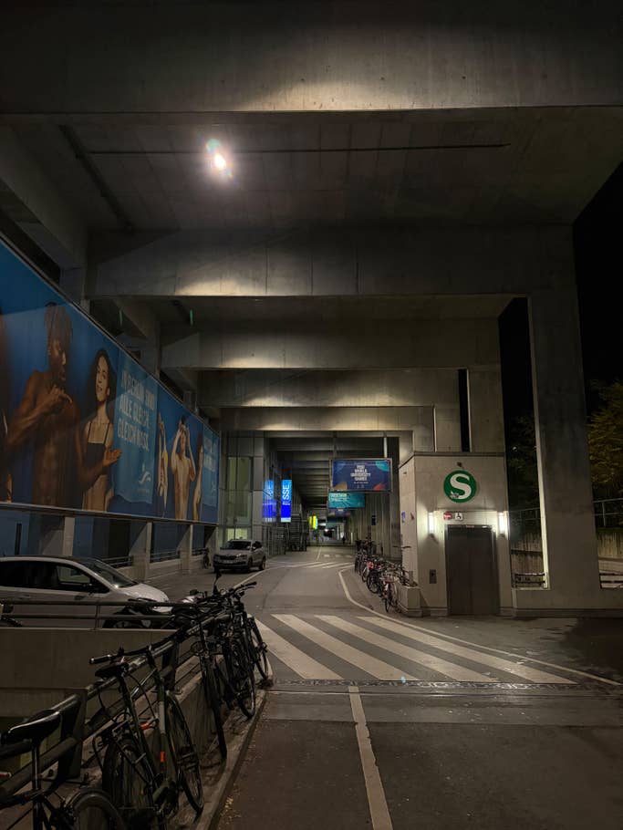 A dimly lit urban passageway with posters on the concrete walls and bicycles parked on the side.