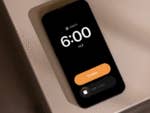 An Apple iPhone displaying an alarm set for 6:00 AM with a 'Snooze' button.