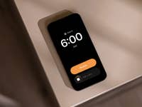 An Apple iPhone displaying an alarm set for 6:00 AM with a 'Snooze' button.