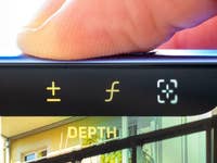 Close-up of an iPhone 16 screen showing depth adjustment buttons and a user's finger hovering above.