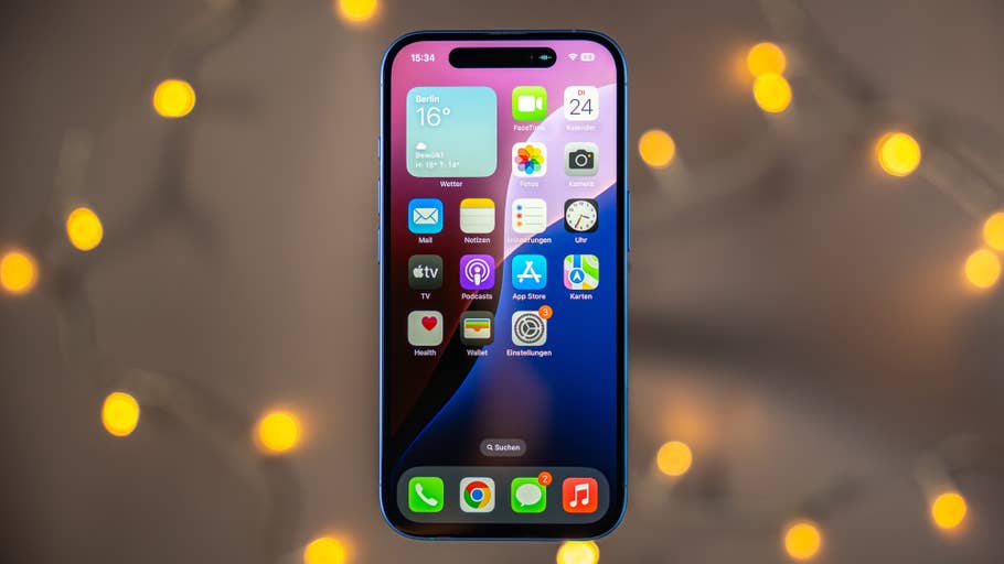 An Apple iPhone 16 shows the home screen with various apps and a weather widget.