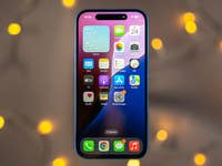 An Apple iPhone 16 displaying the home screen with various apps and a weather widget.