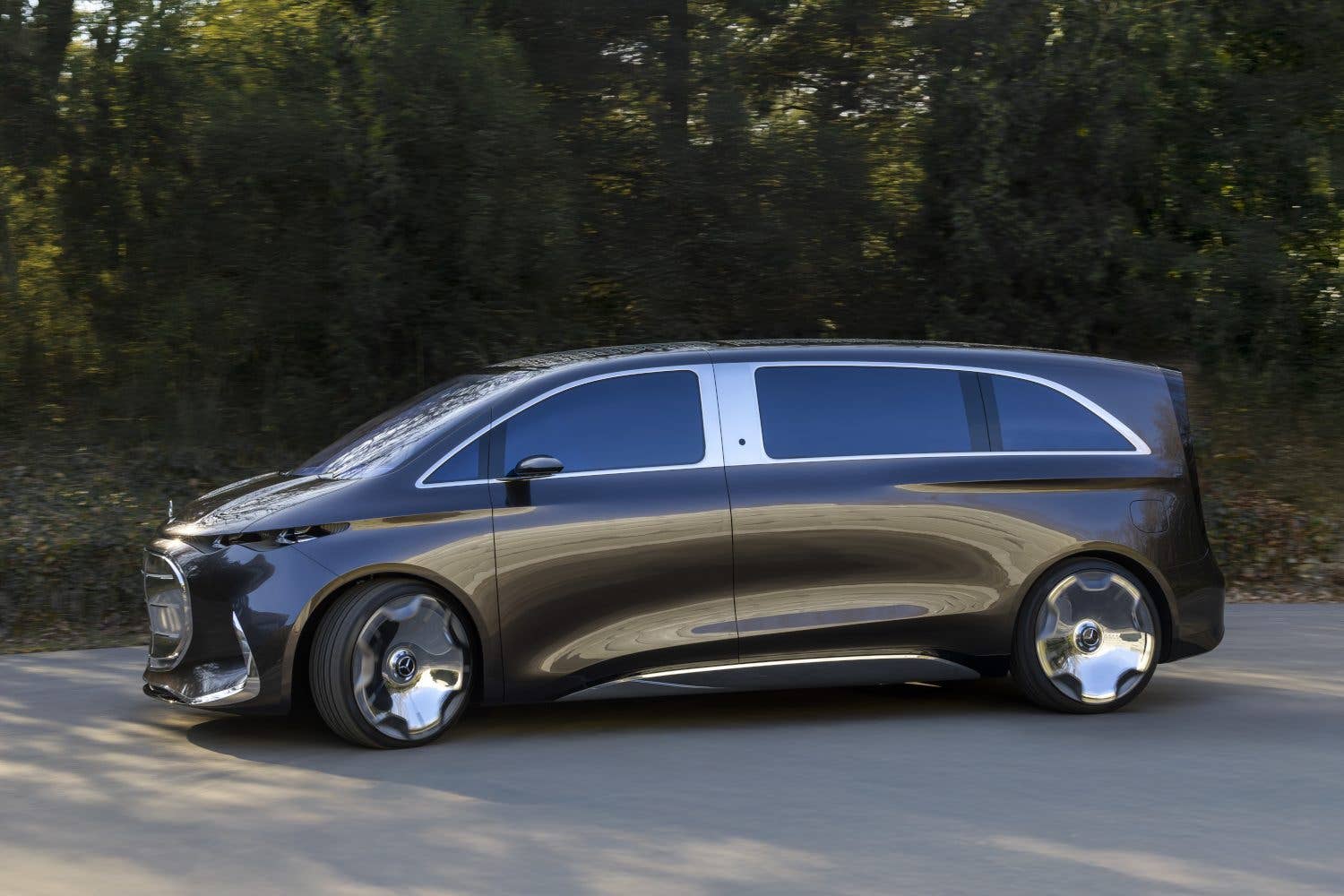 A sleek Mercedes Vision V concept car parked on a road surrounded by trees.