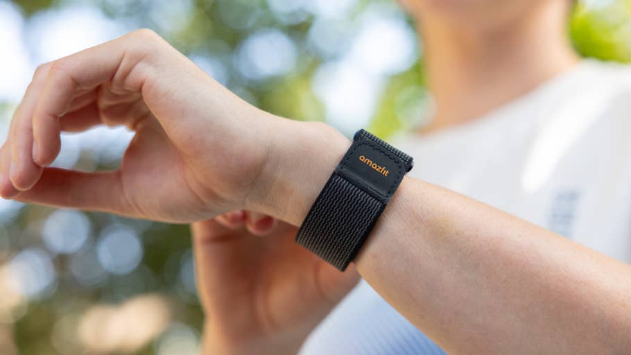 A close-up of a hand wearing an Amazfit Helio strap on a wrist, with a blurred outdoor background.