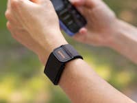 A close-up of a wrist with an Amazfit Helio strap, holding a smartphone.