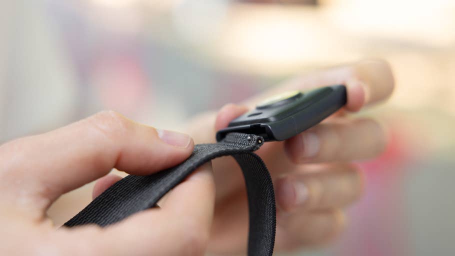A person holding a black strap attached to a device.