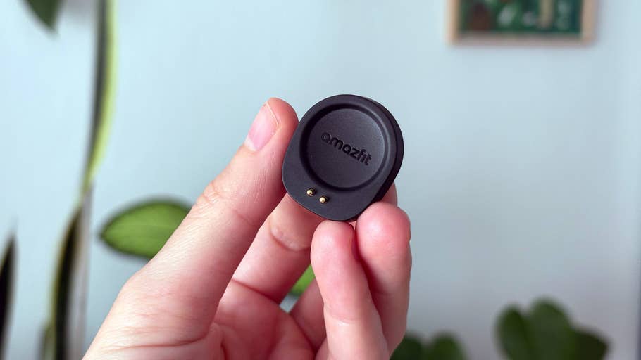 A person holding an Amazfit Helio strap component with a green plant in the background.