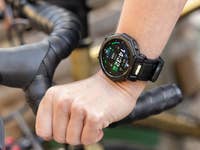 A hand wearing an Amazfit T-Rex Pro 3 smartwatch on a bike handlebar, displaying time and fitness data.