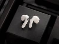 Apple AirPods 4 are available in non-ANC and ANC versions. White Apple AirPods on a black background with stacked boxes.