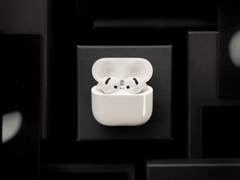 White Apple AirPods in their charging case on a dark background.