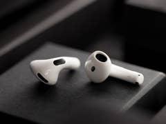 White Apple AirPods on a dark background, showcasing their sleek design.