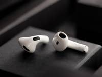 White Apple AirPods on a dark background, showcasing their sleek design.