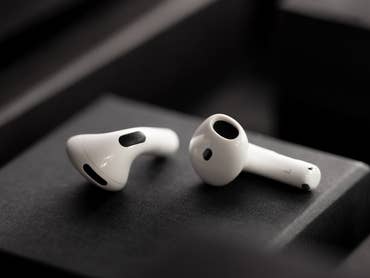 White Apple AirPods on a dark background, showcasing their sleek design.