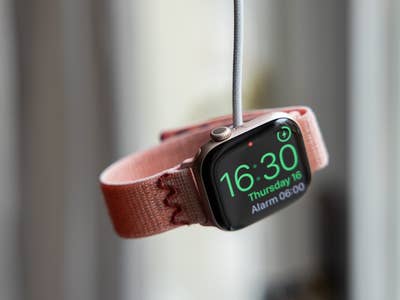A pink Apple Watch displays the time 16:30 on its screen.